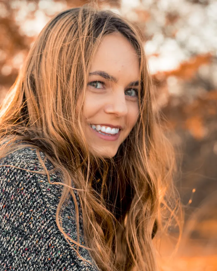 A radiant woman with long hair smiling in warm autumn light